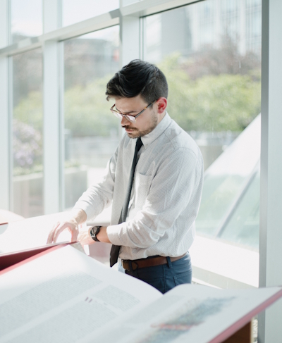 Regent College Library Services Manager Colton Whelpton turns the page of a volume of The Saint John's Bible Heritage Edition on display in the Regent Atrium.